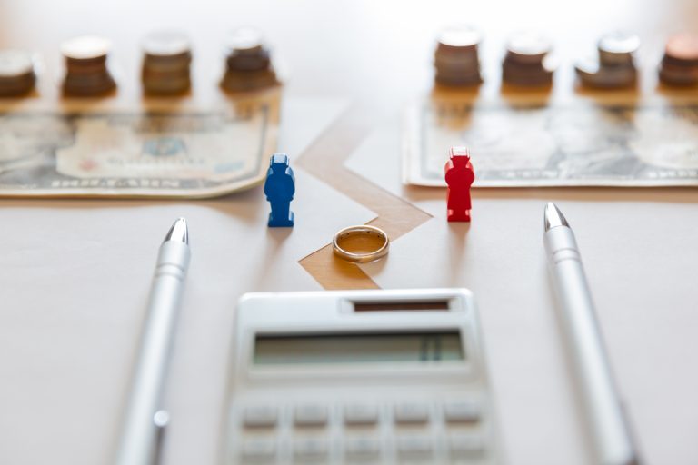 A couple with calculator, paper money, coins, pen and marriage ring in financial troubles.