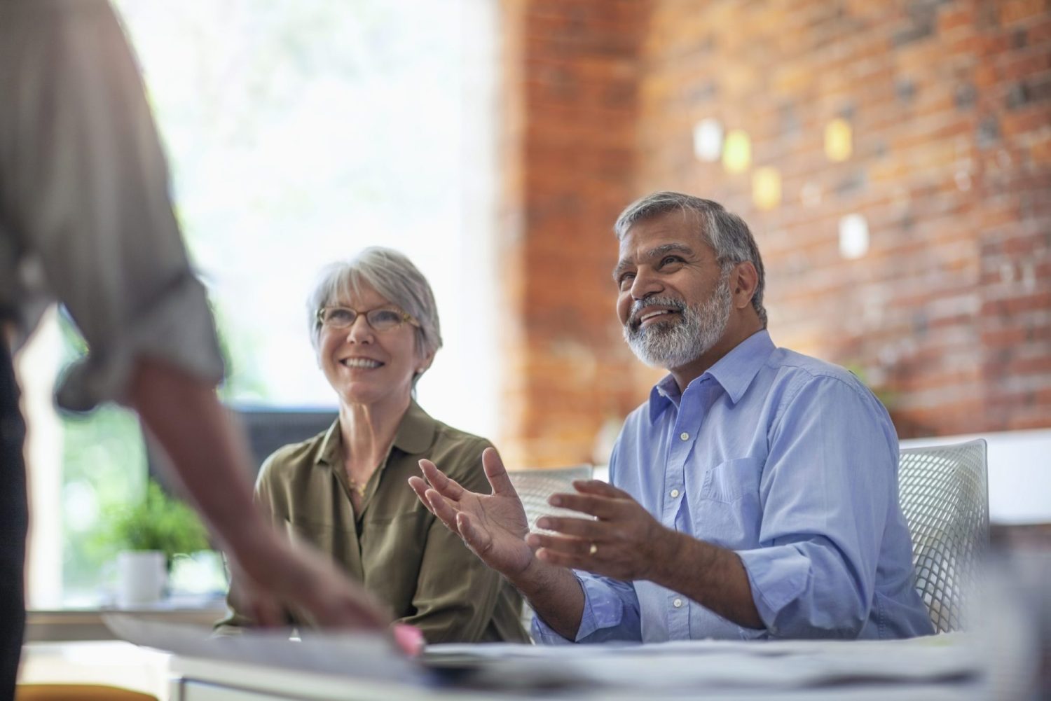 An older couple at a restaurant table, smiling and interacting with a server