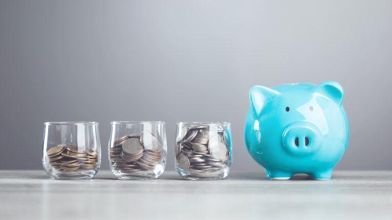 A man dropping coins into a glass jar, with a piggy bank nearby. Represents the concept of saving money, highlighting the importance of building a financial cushion through various saving methods.